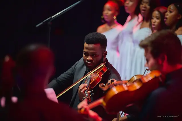 A violinist of the string quartet, with the choir behind
